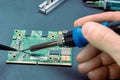 Male hands holding a soldering iron to solder the resistor on the board from the computer. repair of computer equipment