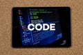 a male hands holding a tablet with the phrase code over a writing code concept and a cork background Royalty Free Stock Photo