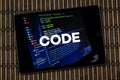 a male hands holding a tablet with the phrase code over a writing code concept and a wooden background Royalty Free Stock Photo