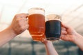 Male hands holding three glass mugs of light and dark draft beer. Beer toast, cheers Royalty Free Stock Photo