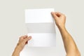 Male hands holding a white booklet triple sheet of paper. Isolated on gray background. Closeup