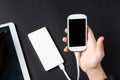 Male hands holding a white cellphone connected to a power bank Royalty Free Stock Photo