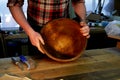 Male hands holding wooden large bowl. Surface treatment in the workshop.