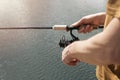 Male hands hoolding spinning rod, spoon-bait and fishing over blue water, close up Royalty Free Stock Photo