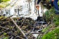 Male hands with  iron shovel destroy the beaver dam, break the dam of  small forest river, expanding the space for the strong flow Royalty Free Stock Photo