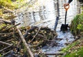 Male hands with  iron shovel destroy the beaver dam, break the dam of  small forest river, expanding the space for the strong flow Royalty Free Stock Photo