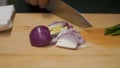 Male hands with knife, cutting fresh onion. Clip. Meal cutting on a wooden board close up. Male hands using a knife cut