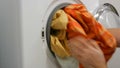 Male hands load a wash of colored laundry into a washing machine and place a capsule with washing powder. Expedited