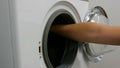 Male hands load a wash of coloured laundry into a washing machine and place a capsule with washing powder. Expedited
