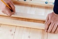 Male hands are marking boards for drilling holes for screws