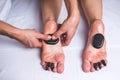 The male hands of the masseur make a foot massage with hot stones.