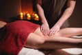 Male hands of the masseur massage the thighs and legs of the client woman