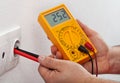 Male hands measuring voltage in electrical wall recepticle