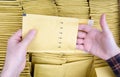 Male hands open a yellow bubble envelope against the open shipping box full of padded mailers.