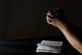 Male hands and opened Bible on the black table against dark wall.Empty space Royalty Free Stock Photo