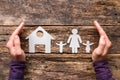 Male hands and paper silhouettes of his wife and children near the house. concept of protection and care Royalty Free Stock Photo