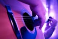 Male hands playing fingers style on a western dreadnought guitar in purple neon light. Royalty Free Stock Photo