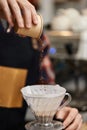 male hands pouring grounded coffee in filter.