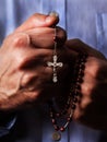 Male hands praying holding a beads rosary with Jesus Christ in the cross or Crucifix on black background Royalty Free Stock Photo