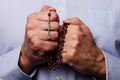 Male hands praying holding a beads rosary with Jesus Christ in the cross or Crucifix Royalty Free Stock Photo