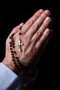 Male hands praying holding a rosary with Jesus Christ in the cross or Crucifix on black background. Royalty Free Stock Photo