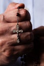 Male hands praying holding a rosary with Jesus Christ in the cross or Crucifix on black background. Royalty Free Stock Photo