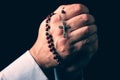 Male hands praying holding a rosary with Jesus Christ in the cross or Crucifix Royalty Free Stock Photo