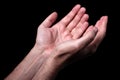 Male hands praying with palms up arms outstretched. Black background. Royalty Free Stock Photo