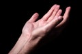 Male hands praying with palms up arms outstretched. Black background. Royalty Free Stock Photo