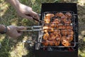 Male hands preparing grilled chicken meat on the grill. Picnic outdoor horizontal photography