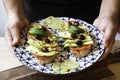 Male hands present avocado toasts on ceramic dish. Fresh vegetarian ingredients used on brunch meal. Bruschetta, Avocado, Tomato, Royalty Free Stock Photo