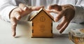 Male hands protecting the piggy bank house on the table. Real estate insurance concept Royalty Free Stock Photo