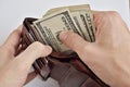 Male hands pulling a pile of American bank notes USD currency, US Dollars from a leather wallet Royalty Free Stock Photo