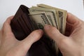 Male hands pulling a pile of American bank notes USD currency, US Dollars from a leather wallet Royalty Free Stock Photo