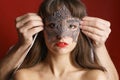 Male hands put lace mask on face beautiful girl with red lipstick on red Royalty Free Stock Photo