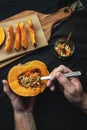 Male hands removing seeds with spoon from a fresh cut pumpkin on black background Royalty Free Stock Photo