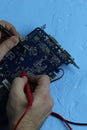 Male hands repair an electronic device using Multimetr, measuring the voltage of the computer motherboard with  digital multimeter Royalty Free Stock Photo