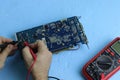 Male hands repair an electronic device using Multimetr, measuring the voltage of the computer motherboard with  digital multimeter Royalty Free Stock Photo