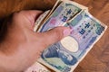 Male hands showing banknotes from Japan on a wooden background Royalty Free Stock Photo