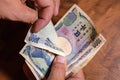 Male hands showing banknotes from Japan on a wooden background