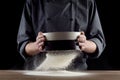 Male hands sifting flour from old sieve on old wooden kitchen table. Isolated on black background. Royalty Free Stock Photo