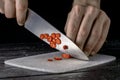 Male hands slicing rings of red hot chili pepper with a sharp knife. Chef cutting spicy cayenne peppers into thin slices Royalty Free Stock Photo