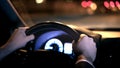 Male hands on steering wheel, backseat shot with view on road at night