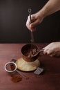 Male hands stirs melted chocolate swirl in pan on the wooden background Royalty Free Stock Photo