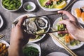 Male hands take pictures of fresh oysters with mobile phone. Top view. Young man taking a photo of a plate of oysters on a