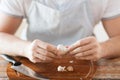 Male hands taking off peel of garlic on board