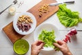 Male hands tearing lettuce leaves over a plate.