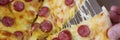 Male hands tearing off slice of pizza with cheese and sausage close-up Royalty Free Stock Photo