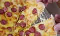 Male hands tearing off slice of pizza with cheese and sausage close-up Royalty Free Stock Photo