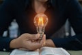 Male hands touching to light bulb which have mechanical gear inside on open book for creative thinking of problem solving and Royalty Free Stock Photo